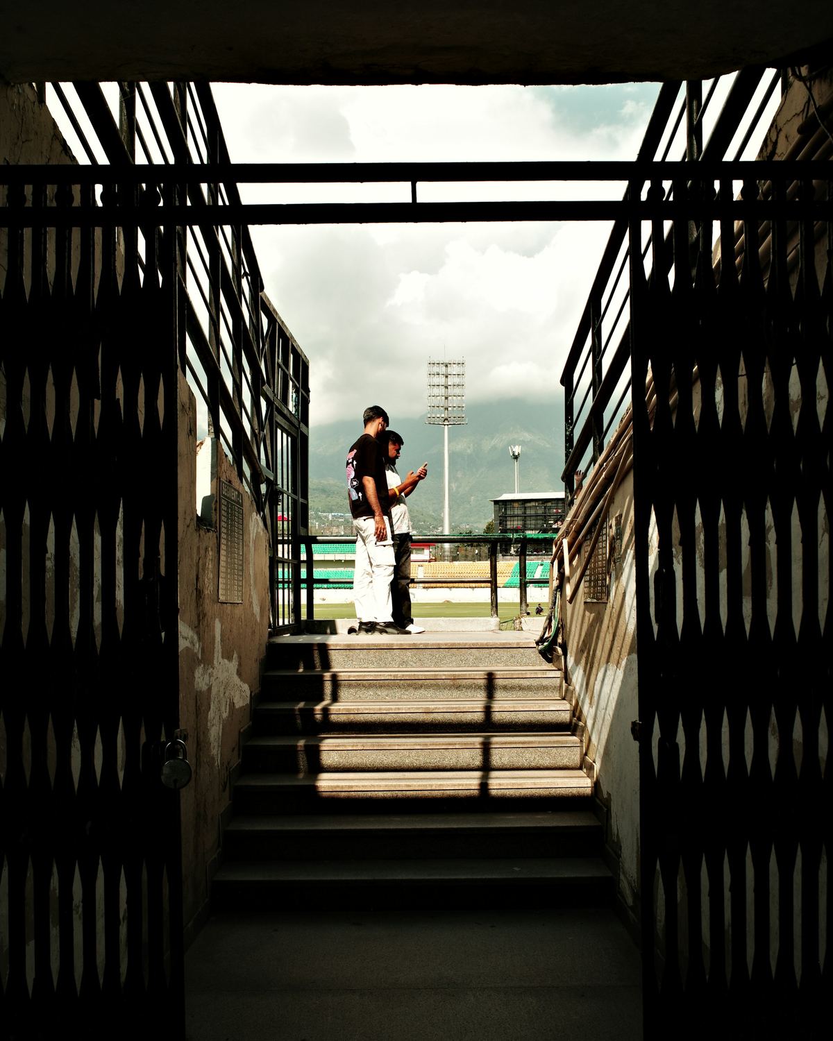 Two people at the top of a stadium tunnel, the pitch beyond.