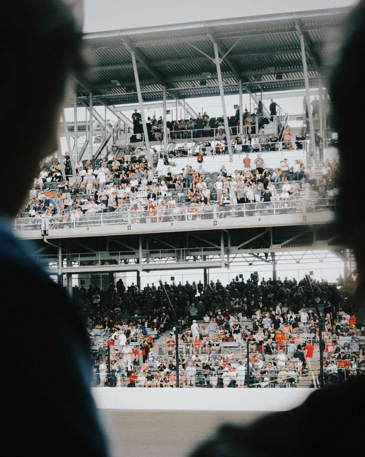 Two spectators seen from behind, facing a full stand.