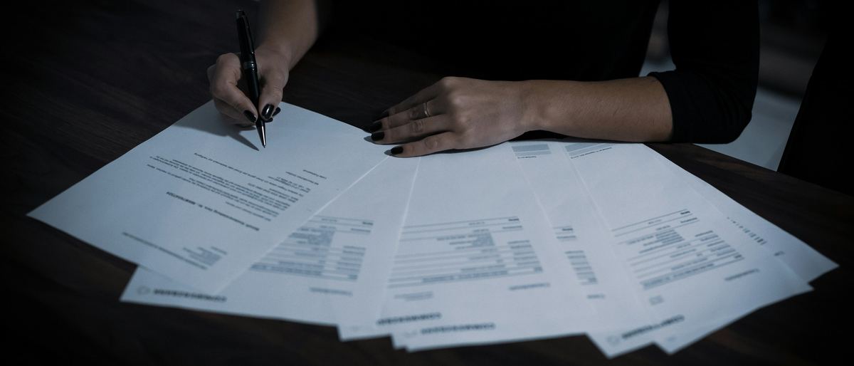 Hands reviewing and signing a set of documents.