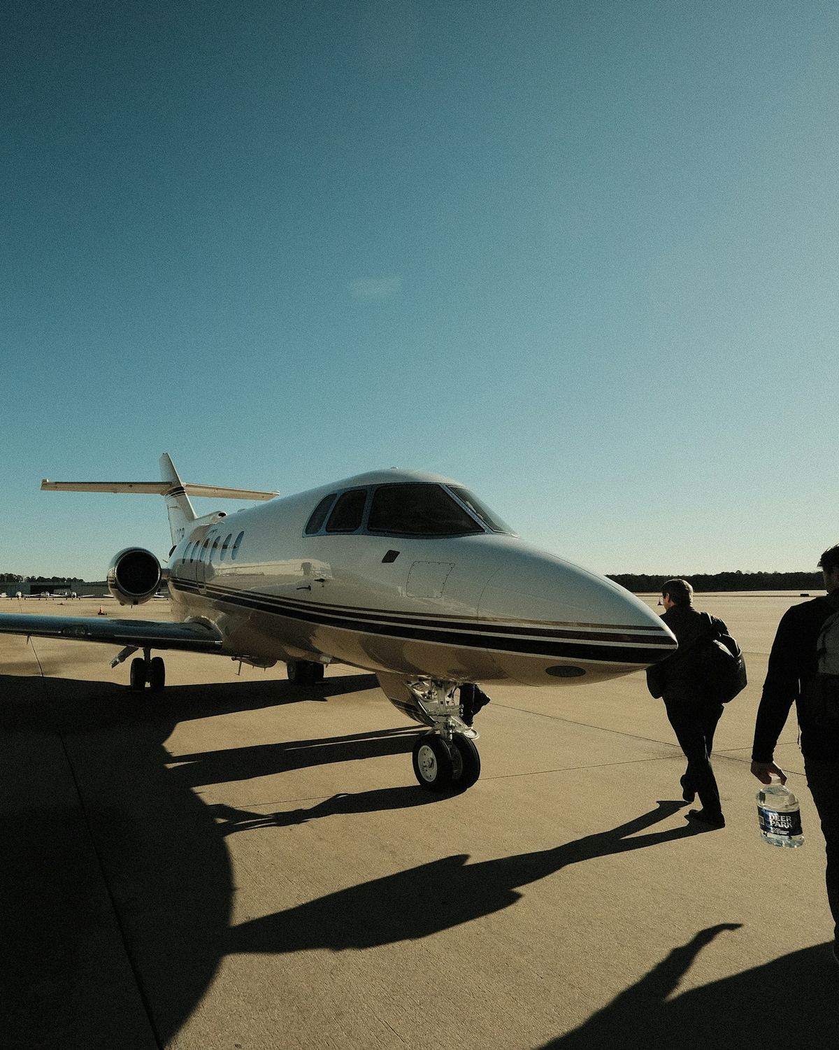 Travellers walking across the tarmac towards a waiting jet.