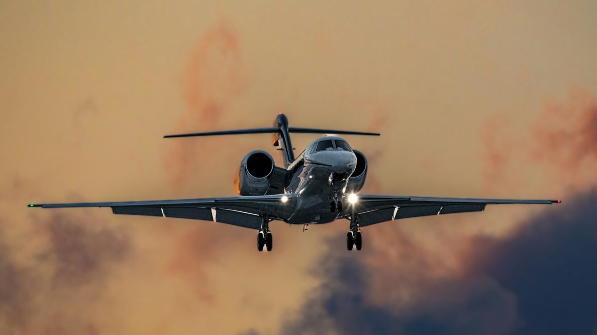 A private jet in flight above clouds at sunset.